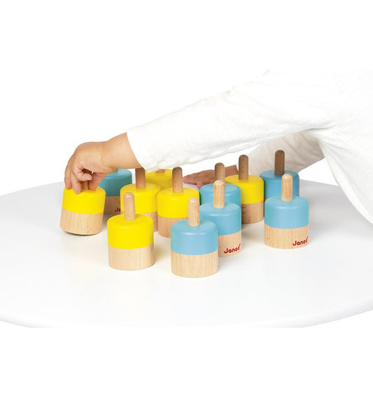 Niño jugando con memo sonoro de madera de Janod en colores amarillo y azul sobre mesa blanca