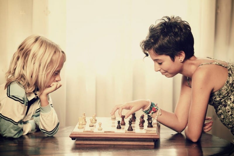 Dos niños jugando ajedrez en una mesa. Conoce los beneficios del ajedrez en niños
