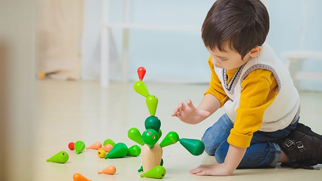 Niño pequeño jugando con juguetes educativos en casa apoyando el desarrollo infantil de 0 a 6 años