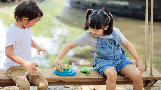 Niños pequeños jugando juntos al aire libre con juguetes educativos para el desarrollo infantil de 0 a 6 años