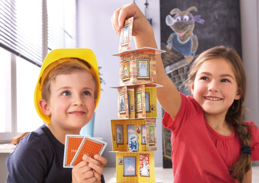 Niños jugando al juego de mesa Super Rino construyendo una torre con cartas en una reseña del juego de mesa Super Rino