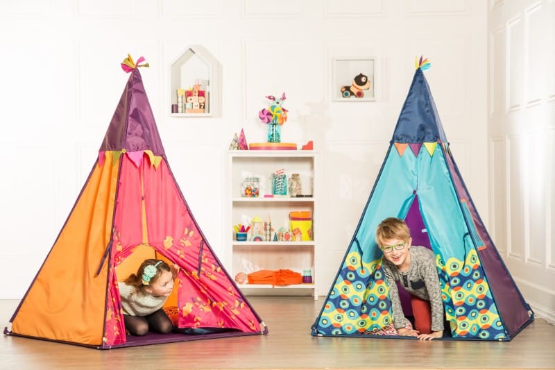 Niños jugando en tiendas de campaña de colores en habitación con juguetes educativos B You