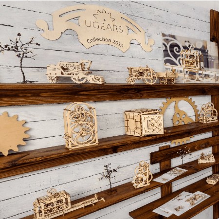 Maquetas mecánicas de madera Ugears exhibidas en estantes de madera en tienda Cucutoys