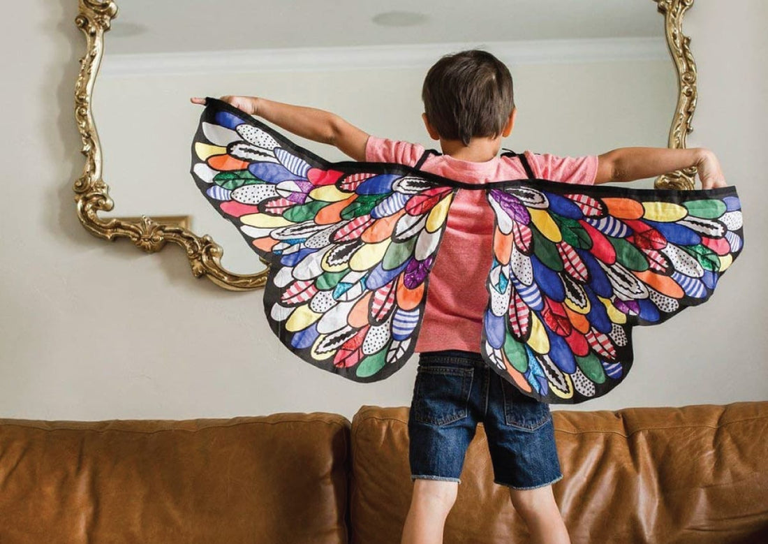 Niño con alas coloridas pintadas a mano jugando en casa. Manualidades fáciles para niños en casa