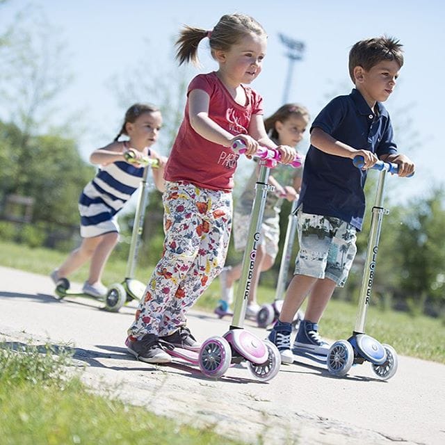Niños aprendiendo a andar en patinete al aire libre con equilibrio y diversión. Cómo saber si mi hijo está listo para un patinete