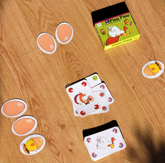 Reseña del juego de cartas Piou Piou mostrando sus cartas coloridas y su caja sobre una superficie de madera