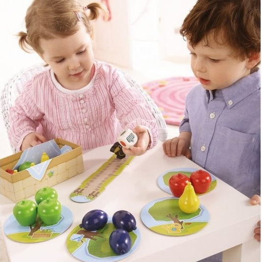 Niños jugando con primer frutal juego educativo de HABA para aprender frutas y cooperar en familia